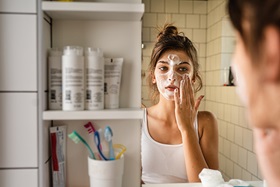Woman applying skin care product on face.